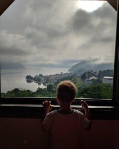een jong kind dat uit een raam naar het water kijkt bij B&B Jonovic in Donji Milanovac