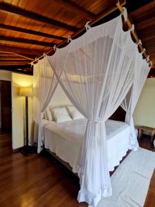 a bedroom with a canopy bed with white curtains at Casa Mia Pousada in Cabedelo