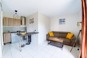 een woonkamer met een bank en een keuken bij Le Lumineux-T2-43m2-Face Val d'Europe-Disney in Serris
