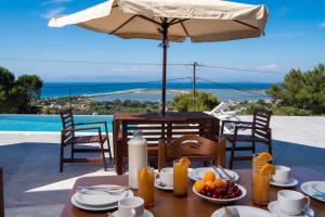 a table with an umbrella and a table with food on it at Voula Villa Luxury in Lefkada Town