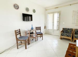 uma sala de estar com uma mesa e cadeiras e uma televisão em 52H Green leaves Village, families & couples only em Dawwār Abū Duray‘ah ‘Abd al Karīm