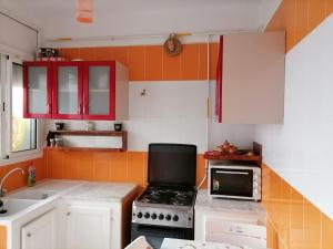 una cucina con armadi rossi, piano cottura e forno a microonde di Hergla_AFH_Beach a Harqalah