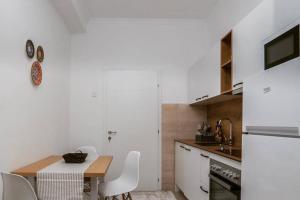 a white kitchen with a wooden table and white chairs at Mickitos Apartments at Macedonia Square in Skopje