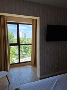a bedroom with a large window and a flat screen tv at Alfa Relax Apartments in Saturn