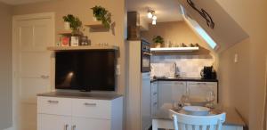 a kitchen with a flat screen tv and a table and chairs at Appartement Marigold in Zandvoort