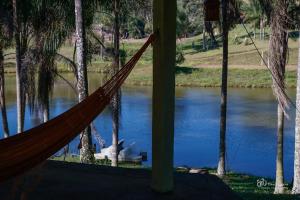 a hammock in front of a river with a boat at BANGALÕ DO LAGO in Caconde