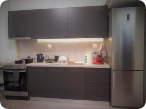 una cucina con mobili neri e un frigorifero in acciaio inossidabile di Petite Palace Rotonda a Salonicco