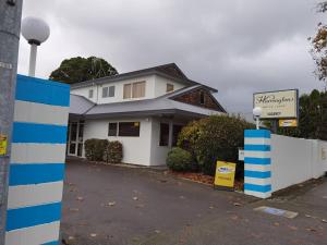 a white house with a sign in front of it at Harringtons Motor Lodge in Palmerston North