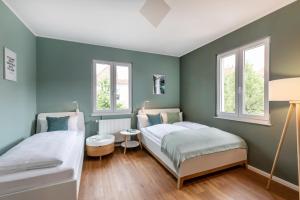 2 camas en una habitación con paredes y ventanas verdes en PRIMERA Villa, en Singen