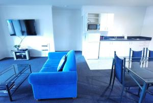 a living room with a blue couch and a table at Harringtons Motor Lodge in Palmerston North