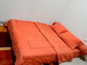 um cobertor laranja sentado em cima de uma cama em Villa Lembang Syariah near park & Zoo em Lembang
