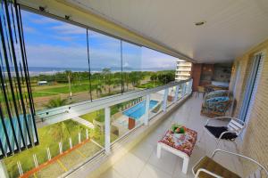 a balcony with a view of a pool and the ocean at LINDO NOVISSIMO e PÉ NA AREIA in Bertioga