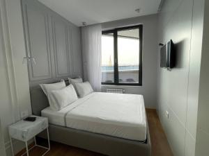 a small bedroom with a white bed and a window at Pupin Palace Apartments in Novi Sad