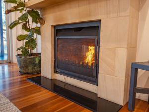 a fireplace in a living room with a fire in it at Fig Tree Luxury Guest House in Pokolbin