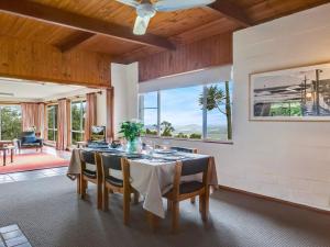 a dining room with a table and chairs and windows at Captain's Lookout in Bellawongarah