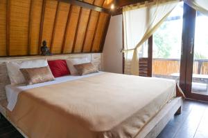 a bedroom with a large bed with a large window at Puri Hondje in Gili Trawangan