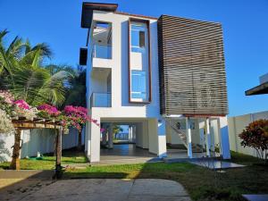 Uma casa branca com flores cor-de-rosa à frente. em Casa de Mateo - Zorritos - Tumbes em Zorritos