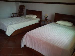 two beds in a hotel room with white sheets at Javier Guesthouse in Tbeng Meanchey