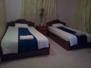 two beds in a hotel room withskirts at Javier Guesthouse in Tbeng Meanchey