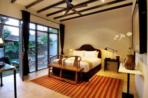 a bedroom with a bed and a table with a bench at Room & Vespa 1 in Seminyak