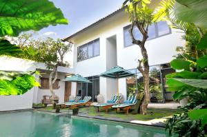 a villa with a swimming pool with chairs and umbrellas at Room & Vespa 1 in Seminyak