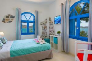 a bedroom with blue windows and a bed with a stuffed animal on it at Eleftheria Sea Side Traditional House in Elounda