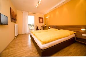 a bedroom with a large bed with a yellow blanket at Gasthof Wösner in Münzkirchen