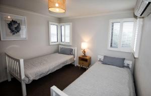 a bedroom with two beds and two windows at FLINDER's REST in Queenscliff