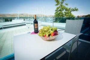 eine Flasche Wein und eine Schale Obst auf dem Tisch in der Unterkunft Azzurro Luxury Rooms Trogir in Trogir