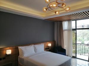 1 dormitorio con cama, ventana y lámpara de araña en Mazeki Addis Boutique Hotel en Addis Abeba