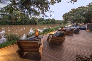 a wooden deck with chairs and tables next to a river at Abelana River Lodge in Phalaborwa