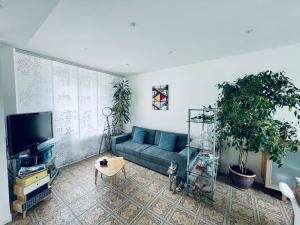 a living room with a blue couch and a tv at le numero 100 in Nancy