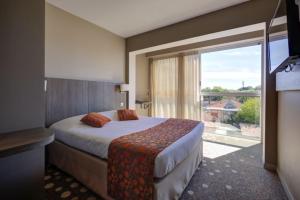 a hotel room with a bed and a large window at Hôtel Le Nautic in Arcachon