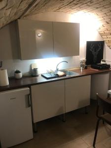 uma cozinha com armários brancos e um lavatório em Kisudvaros Apartman em Vác