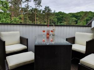 - une table avec 2 chaises et des verres à vin sur le balcon dans l'établissement Dünenpark Binz - Komfort Ferienwohnung mit 1 Schlafzimmer und Balkon im Dachgeschoss 282, à Binz