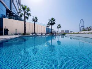 a large swimming pool with palm trees and a roller coaster at KeyHost - The Address Beach Residence - K1360 in Dubai