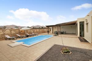 un patio trasero con piscina y una casa en Casa Rural Teberite en Tuineje
