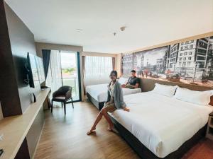 una mujer sentada en una cama en una habitación de hotel en GLOW Pattaya, en Pattaya South