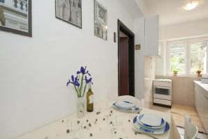 eine Küche mit einem Tisch mit Tellern und Blumen darauf in der Unterkunft Apartments Kalajžić in Pučišća