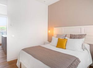 1 dormitorio con 1 cama blanca grande con almohadas amarillas en ALCALA III, en Madrid