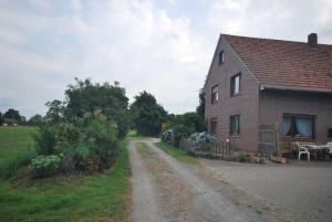 un camino de tierra junto a una casa de ladrillo en Ferienhof Wiesenblick 35519, en Uplengen