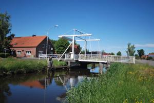 un puente sobre un río junto a una casa en Ferienhof Wiesenblick 35519, en Uplengen