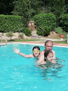 een man en twee kinderen in een zwembad bij RoccaiaCasa'70 in San Gimignano
