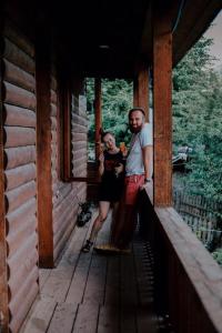 un hombre y una mujer parados en un porche de una cabaña en Teo Guesthouse and Camping in Mestia, en Mestia