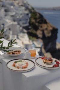 een tafel met drie borden eten erop bij Panorama Suites in Fira