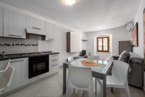 a kitchen with a table and white chairs in a room at Apartments Dante in Umag