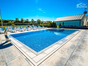 a swimming pool with lounge chairs and a swimming pool at Balticus in Jarosławiec
