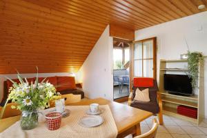 a living room with a wooden ceiling and a table at Hof Wagenberg Ferienwohnung 2 in Deggenhausertal