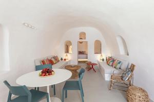 una sala de estar blanca con mesa blanca y sillas en White Cave by Caldera Houses, en Oia