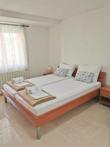 1 dormitorio con 1 cama grande con sábanas y almohadas blancas en Apartment Sara en Njivice